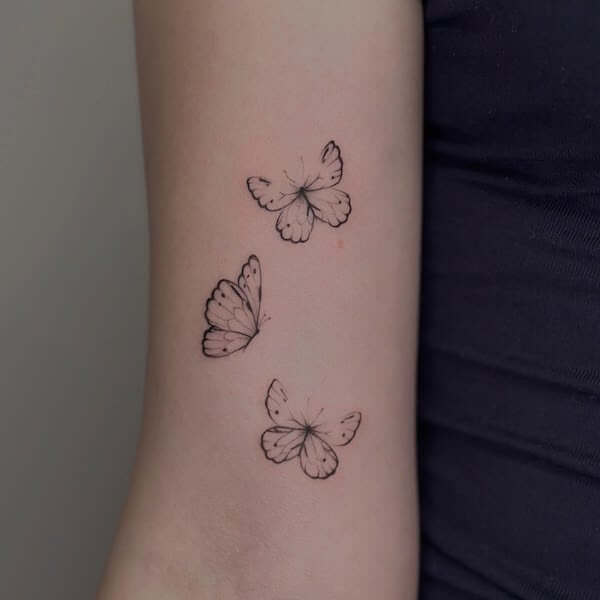 Three Dainty Butterflies Flying Tattoo On Upper Arm